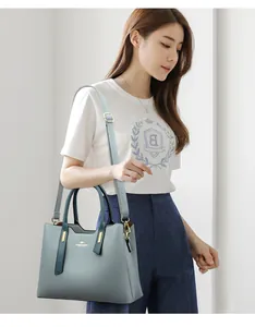 Modella asiatica che mostra un'elegante borsa in pelle PU verde acqua con dettagli oro