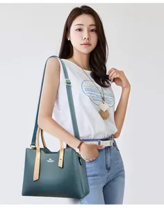 Modella asiatica che indossa una borsa a tracolla in pelle PU bicolore verde acqua