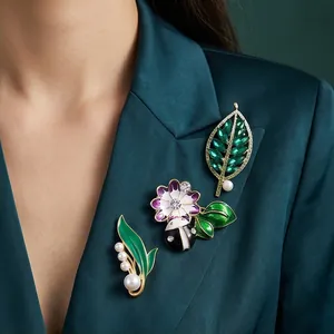 Elegantes Emaille-Broschen-Set mit grünen Blättern und Blumen und Perlen auf Satin-Blazer