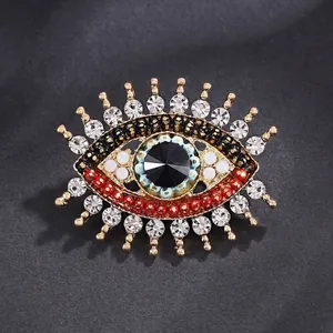 Elegant evil eye brooch with crystals and black stone for suit lapels, gold finish.