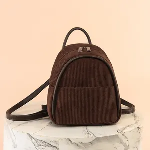 Small brown corduroy backpack for women on a marble display stand