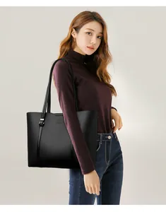 Vista detallada de un gran bolso tote de cuero negro llevado por una modelo femenina.