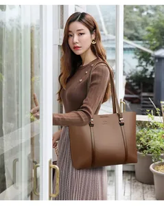 Elegante bolso tote marrón de gran capacidad lucido por modelo en un ambiente exterior