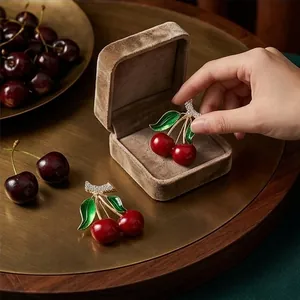 Elegant red enamel cherry brooch with crystal accents presented in a luxury gift box