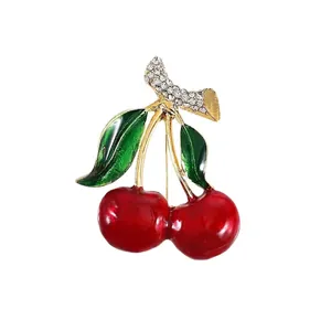 Elegant red enamel cherry brooch with sparkling crystal accents on a clean white background