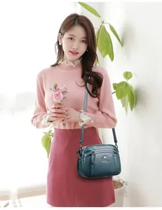 Elegante groenblauwe crossbodytas van kunstleer met ritsen gedragen door een Aziatisch model