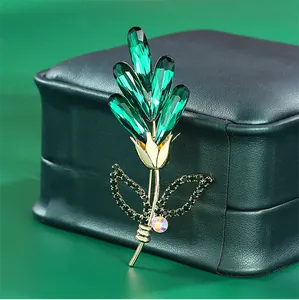 Detailed view of emerald green crystal flower brooch with gold plated brass finish