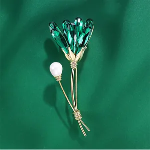 Close-up of elegant flower brooch with green crystals and pearl detail