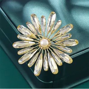 Macro detail of elegant sunburst brooch with champagne K9 glass and white pearl center.