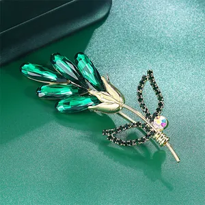 Macro view of a green K9 crystal rose brooch with 14k gold plated brass finish.