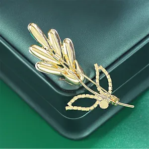Back view of gold rose brooch showing secure pin clasp on green leather box.