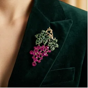 Elegant rhinestone grape brooch on green velvet blazer for stylish accessorizing.