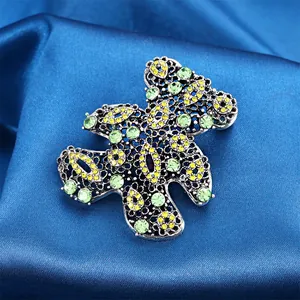 Detailed macro shot of vintage hollow teddy bear brooch with green and yellow rhinestones