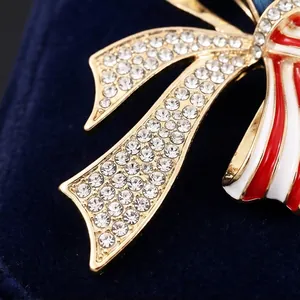 Detalle de broche de lazo con pedrería y esmalte rojo y blanco sobre terciopelo