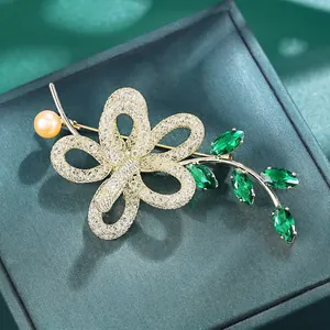 Elegante bloemenspeld met groene K9-kristallen en zoetwaterparel in 14k goudlaag