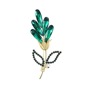 Elegant flower brooch with green teardrop crystals and 14k gold plating on white background
