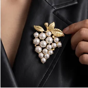 Eleganter Weintraube-Brosche mit weißen Perlen und Goldblättern auf schwarzer Lederjacke