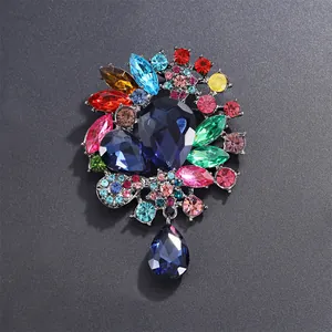 Gros plan d'une broche de style palais vintage avec strass colorés et pendentif goutte.