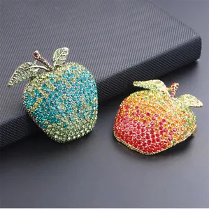 Close-up of luxury rhinestone apple brooches featuring vibrant red and green gradients.
