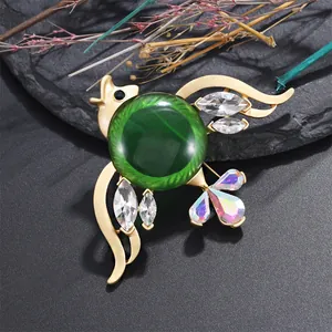 Detalle de elegante broche de pez tropical con un gran cristal verde y acabado dorado