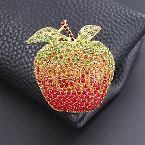 Macro detail of a sparkling rhinestone apple brooch on a black leather background