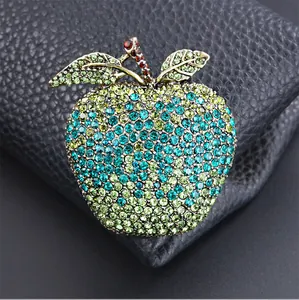 Close-up of sparkling apple brooch featuring green and blue rhinestones