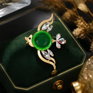 Elegante broche de pez dorado con piedra verde esmeralda y cristales muy brillantes