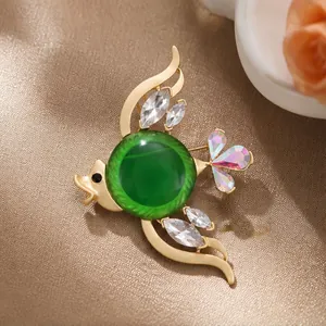 Elegante broche de pez tropical con cristal verde y detalles refinados en tono dorado