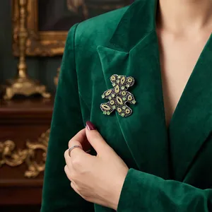 Elegant hollow teddy bear brooch with emerald and yellow crystals on a green velvet blazer