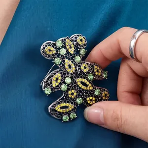 Vintage hollow-out teddy bear brooch featuring vibrant green and yellow rhinestones