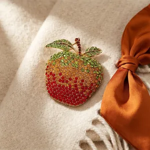 Sparkling apple brooch with colorful rhinestones on elegant knit fabric background