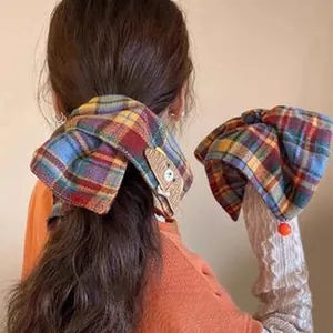 Close-up detail of a large vintage plaid bow scrunchie hair tie shown on hair