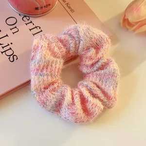 Detailed macro shot of a fuzzy pink knit scrunchie on a minimalist pink aesthetic background