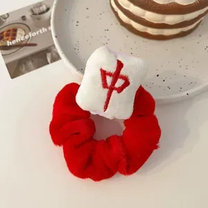 Close-up of a red plush hair scrunchie featuring a white Mahjong Zhong tile charm