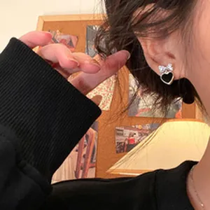 Close-up view of elegant black heart magnetic clip-on earring with a silver zircon bow