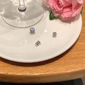 Detail view of elegant zirconia magnetic earrings on a white plate with a rose.