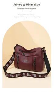 Detail view of burgundy crossbody bag with multi-zipper pockets and ethnic strap.