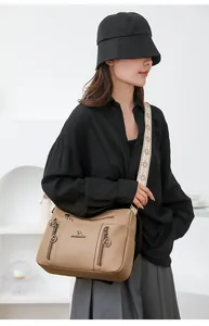 Detail of a khaki pebbled leather crossbody bag with an ethnic style wide strap.