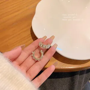 Detail showing elegant C-shaped pearl hoop earrings held in hand for jewelry display