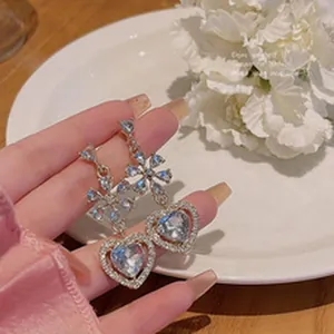 Close-up of sparkling heart-shaped dangle earrings with intricate crystal floral details