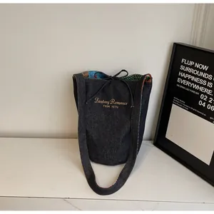 Κομψή τσάντα bucket από βαθύ μπλε denim με χρυσό κέντημα και πολύχρωμη εσωτερική επένδυση