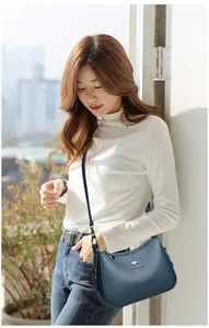 Asian model showcasing a vintage blue soft leather crossbody bag with kangaroo logo