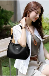 Close-up of black textured leather shoulder bag with kangaroo logo on model