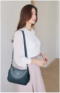 Detailed view of a vintage teal leather shoulder bag worn by a model in a minimal setting.
