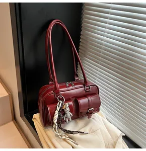 Elegant burgundy women's shoulder bag with front pockets and cute bear charm accessory.