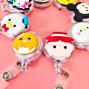 Close-up of colorful cartoon character retractable badge reels on a pink background