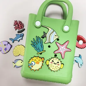 Gedetailleerd overzicht van cartoon zeedieren PVC bedeltjes op een groene EVA-tas