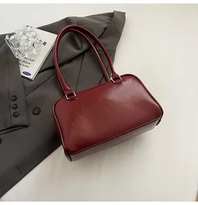 Detailed view of a dark red commuter pillow bag styled with a grey blazer and accessories.