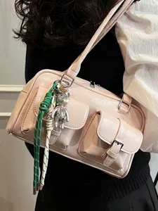 Chic pink leather shoulder bag with pockets and a bear charm accessory.