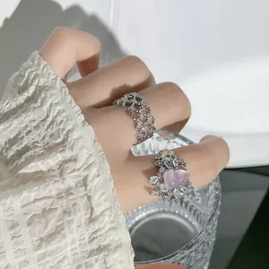 Makro-Detailansicht eines Vintage-Blütenringes mit rosa Herzstein an einer Hand.